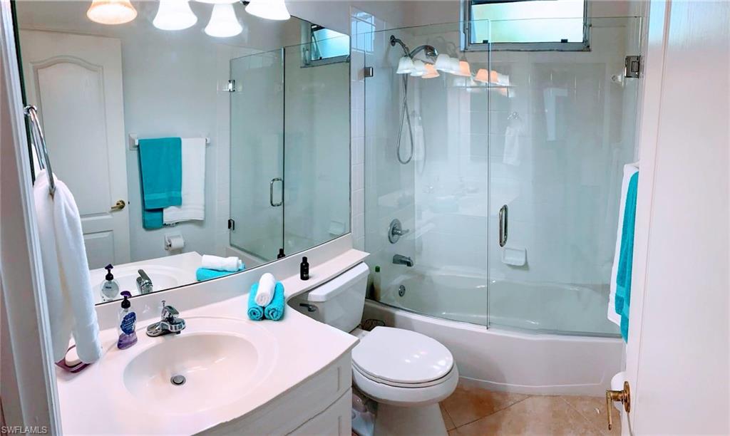 Full bathroom featuring toilet, bath / shower combo with glass door, vanity, and tile patterned floors