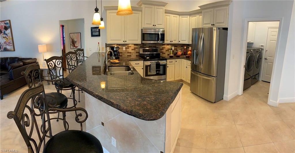 Kitchen with hanging light fixtures, appliances with stainless steel finishes, a kitchen breakfast bar, sink, and kitchen peninsula