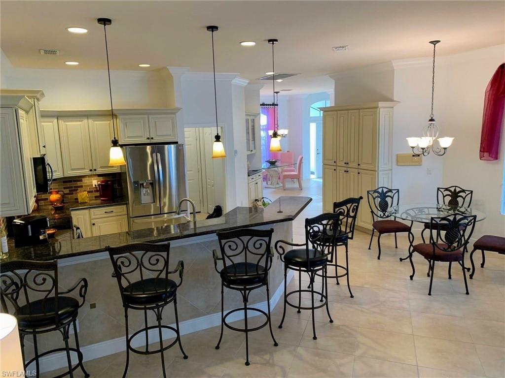 Kitchen with cream cabinets, a notable chandelier, pendant lighting, and stainless steel fridge and a breakfast area