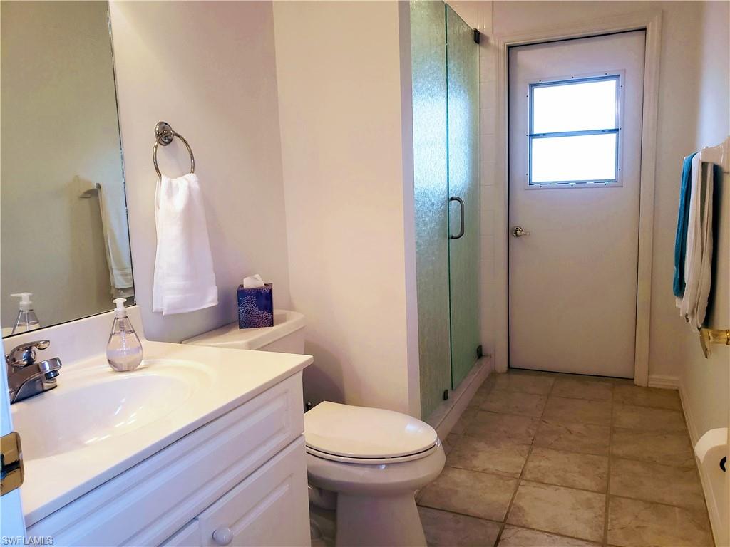 Bathroom featuring an enclosed shower, tile patterned floors, vanity, toilet and patio door.