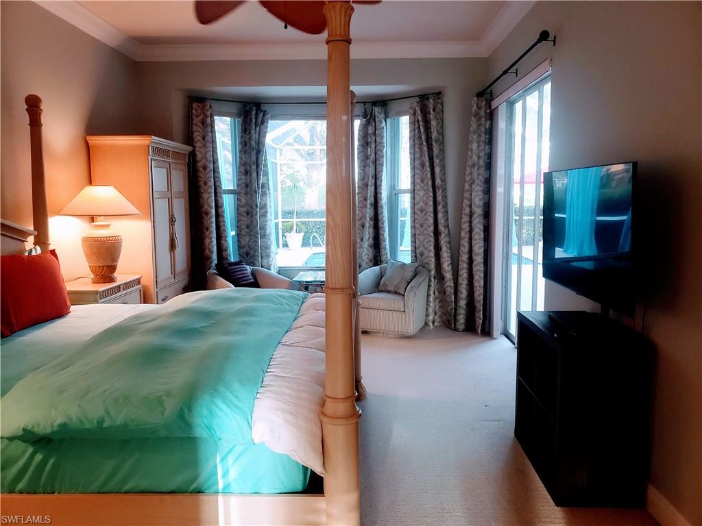 Carpeted bedroom featuring ceiling fan, crown molding, and multiple windows