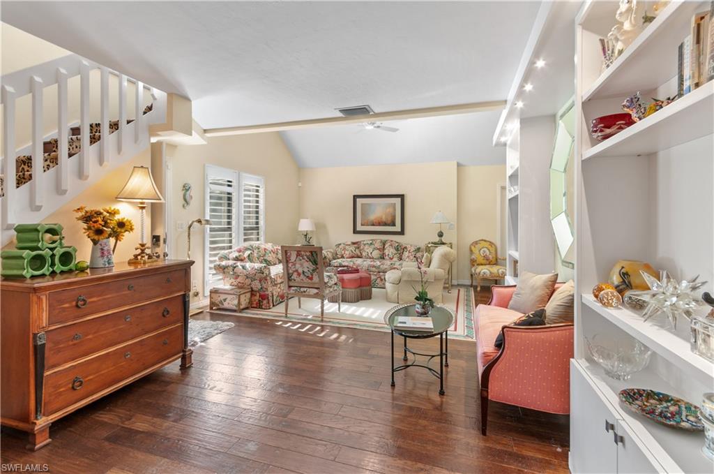 Living room featuring vaulted ceiling, dark wood-style flooring, and ceiling fan