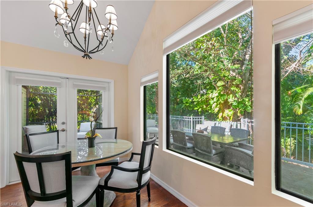 Dining area with dark wood-style flooring, a chandelier, french doors, and lofted ceiling