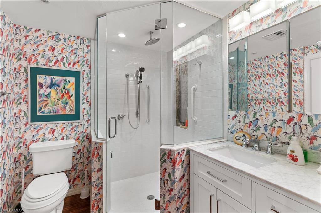 Full bathroom featuring wallpapered walls, birds . vanity, and a shower stall