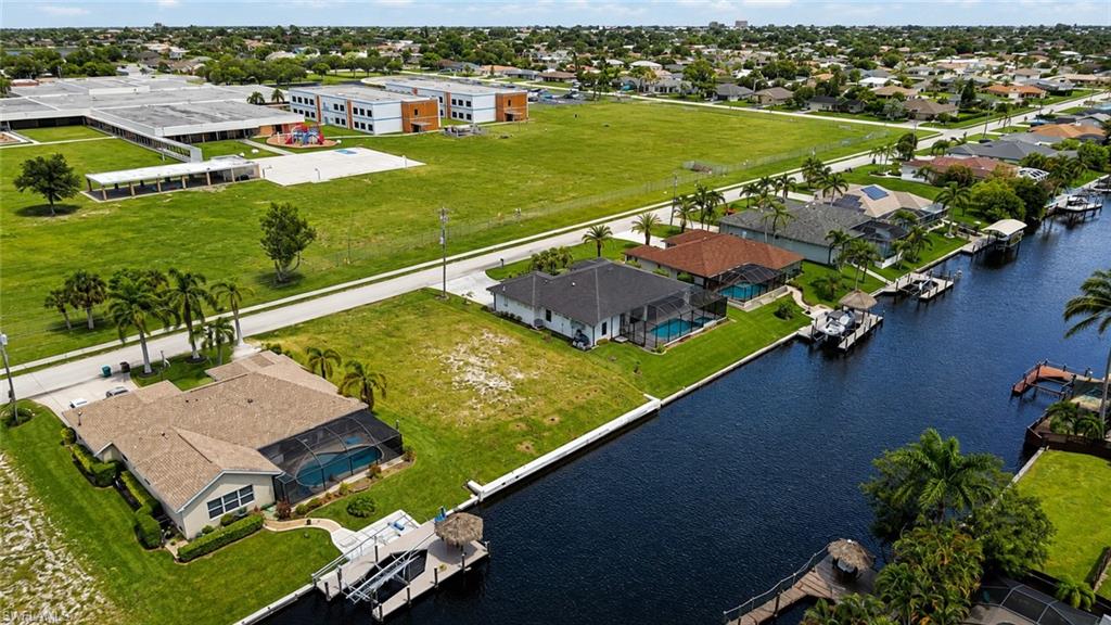 Waterfront property featuring expansive manicured grounds with mature landscaping, direct canal access with boat dock, and multiple residential structures including a primary residence and guest cottage