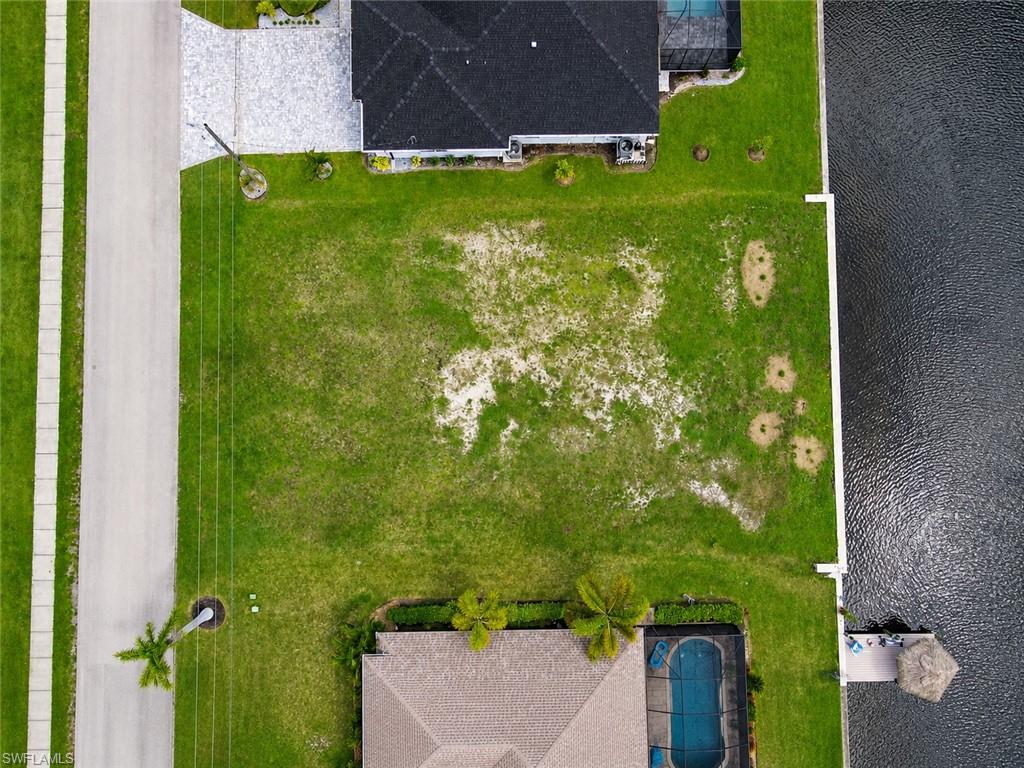 Waterfront lot featuring a spacious manicured lawn with mature tropical landscaping, including palm trees and established plantings