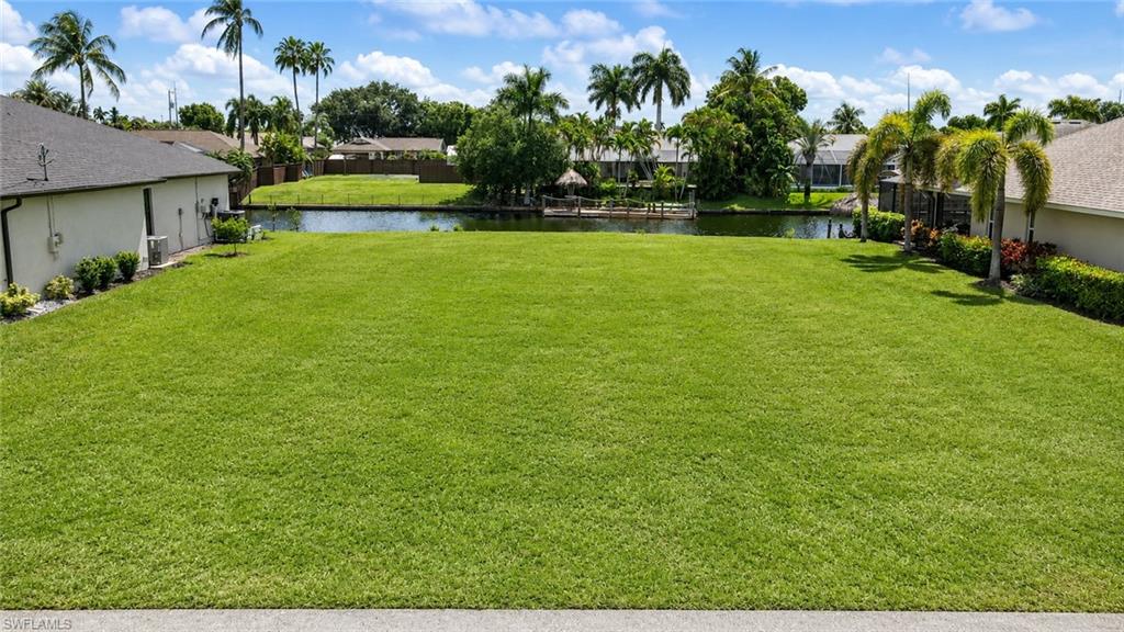 Expansive green lawn with mature palm trees and canal frontage
