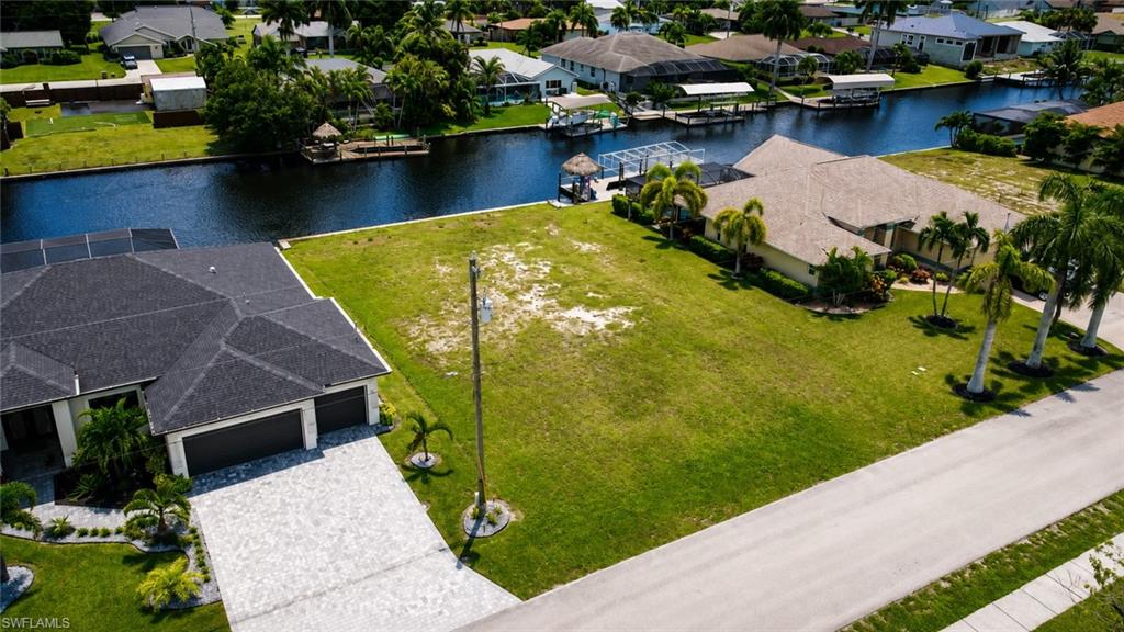 Expansive waterfront lot featuring a manicured lawn, mature palm trees, and direct canal access
