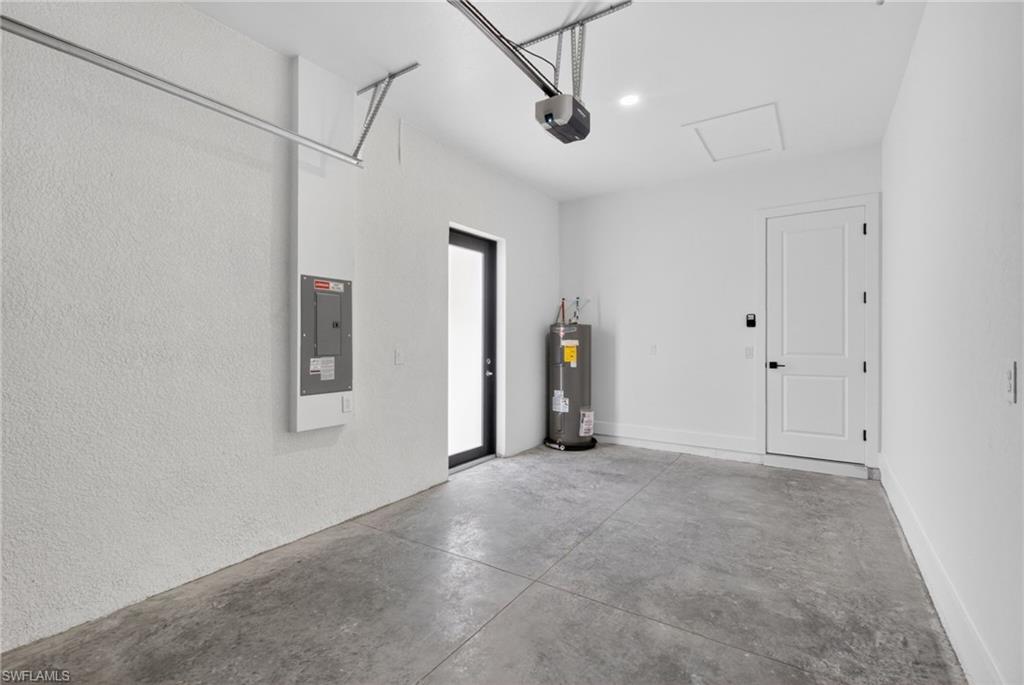 Modern garage space featuring polished concrete flooring, white drywall finish, recessed ceiling lighting, and integrated electrical panel