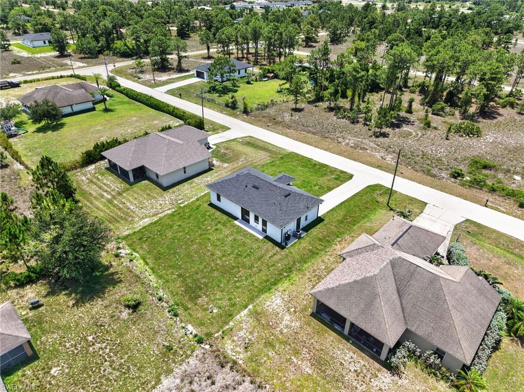 Expansive residential lot featuring multiple single-story homes with dark asphalt roofing, situated among mature landscaping and established trees