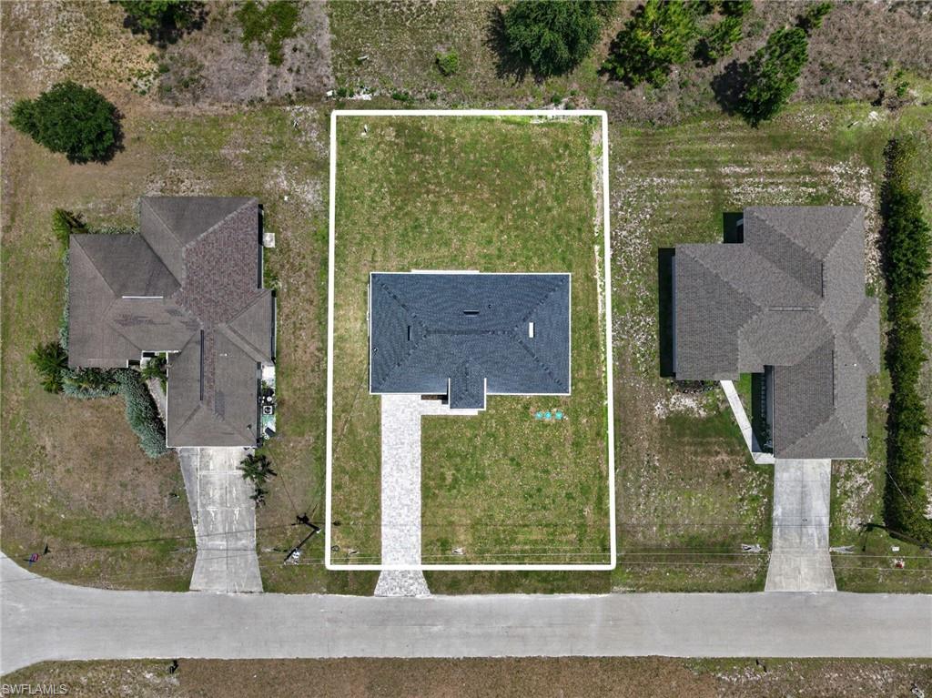 Aerial view showcasing a substantial corner lot with two single-family residences, each featuring dark asphalt roofing and attached driveways