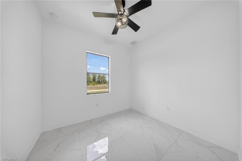 Room featuring white walls, a single window, a ceiling fan with integrated lighting, and large format tile flooring