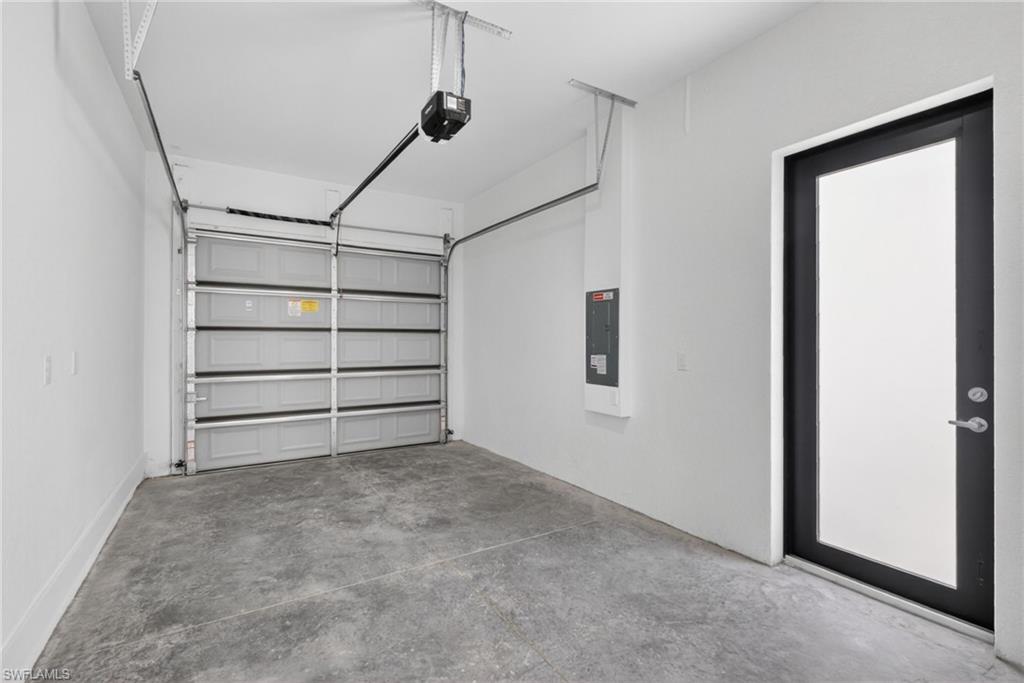 Spacious garage featuring a sectional overhead door with multiple panels, polished concrete flooring, and direct entry via a modern glass-panel interior door