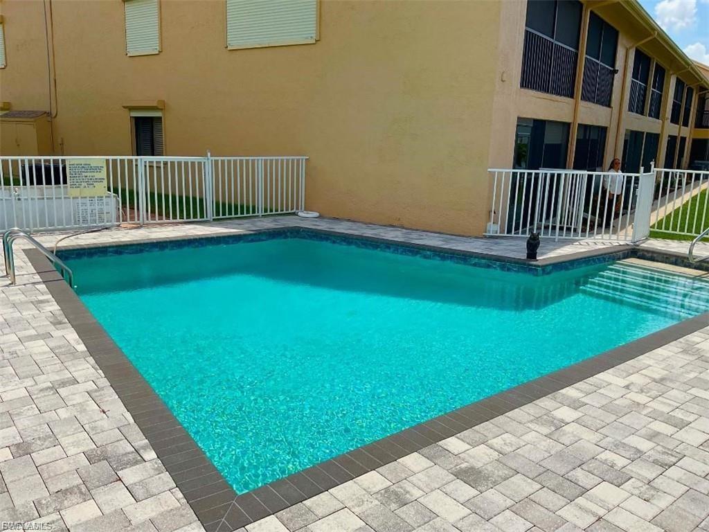 Resort-style swimming pool featuring crystal-clear turquoise water, bordered by textured paver decking and white safety railings