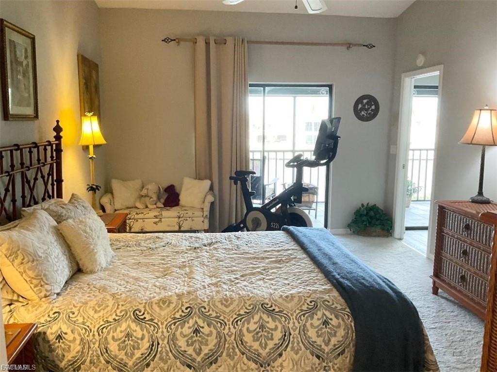 Spacious primary bedroom featuring a decorative upholstered bed frame, coordinated bedding, dual nightstands with table lamps, and abundant natural light from sliding glass doors opening to a private balcony