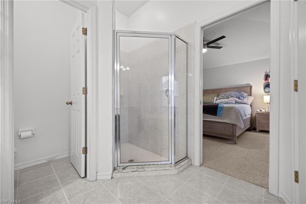 Tile flooring, glass-enclosed shower, vaulted ceiling, and recessed lighting