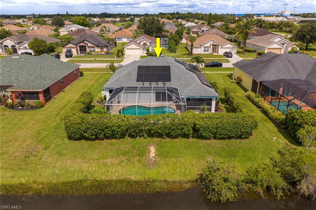 Screened-in swimming pool, solar panel array, mature landscaping, water frontage, and a shingled roof