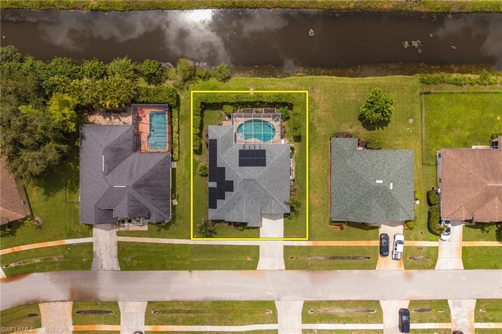 Property featuring a private swimming pool, solar panel installation, paved driveway, and established landscaping