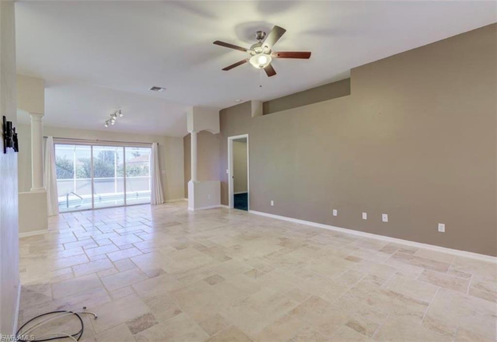 Spacious interior with tile flooring, ceiling fan, and sliding glass doors leading to a screened outdoor area with a pool