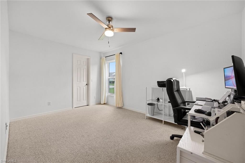 Carpeted room with a ceiling fan, a window, and a paneled door