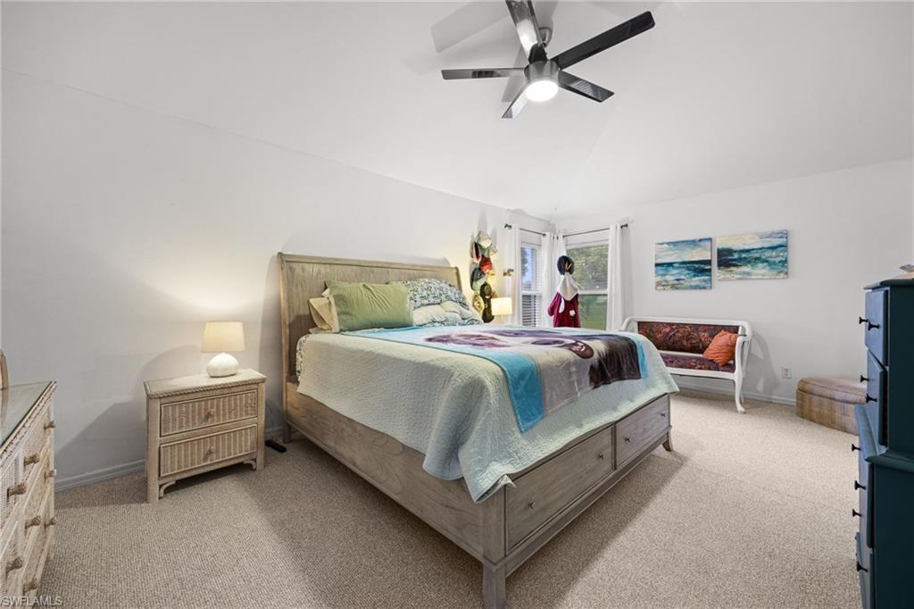 Spacious primary bedroom with vaulted ceilings, ceiling fan, and abundant natural light from multiple windows