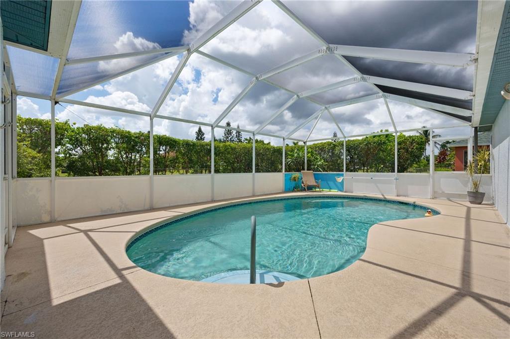 Screened pool enclosure featuring a resort-style saltwater pool with curved design and integrated spa jet