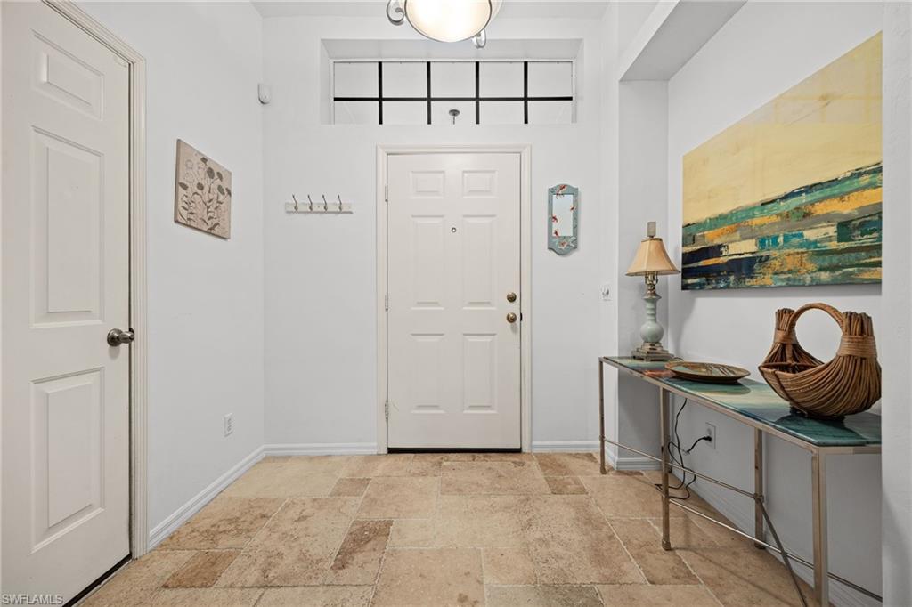 Light-toned tile flooring, white paneled doors, and a transom window