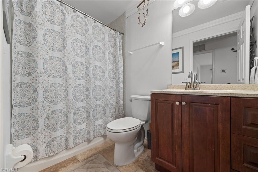 Spa-inspired bathroom featuring a wood-finish vanity with a sink, quartz countertop, and brushed nickel fixtures