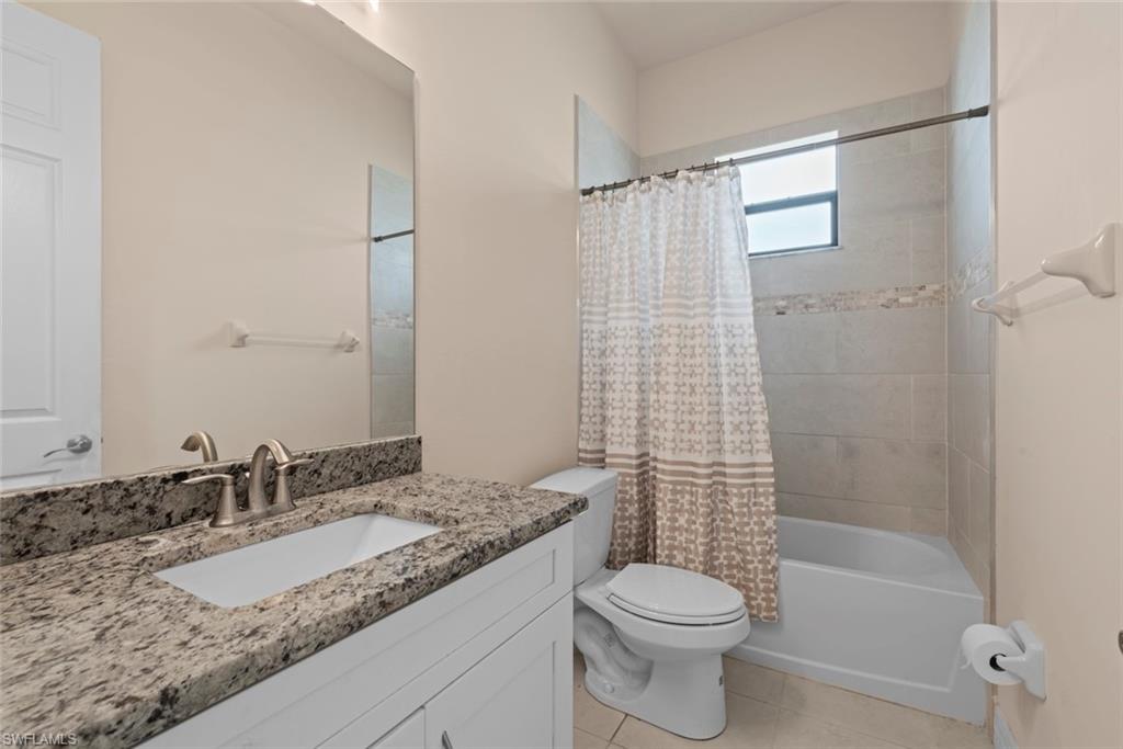 White vanity with granite countertop, undermount sink, and brushed nickel faucet