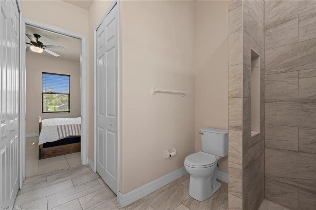 Tiled flooring extending throughout, toilet fixture, built-in shower niche, and bi-fold closet doors