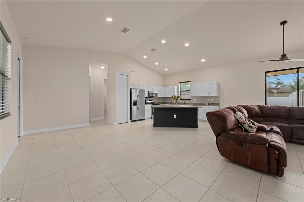 Dining area with vaulted ceilings, recessed lighting, tile flooring, contemporary kitchen island, and stainless steel appliances