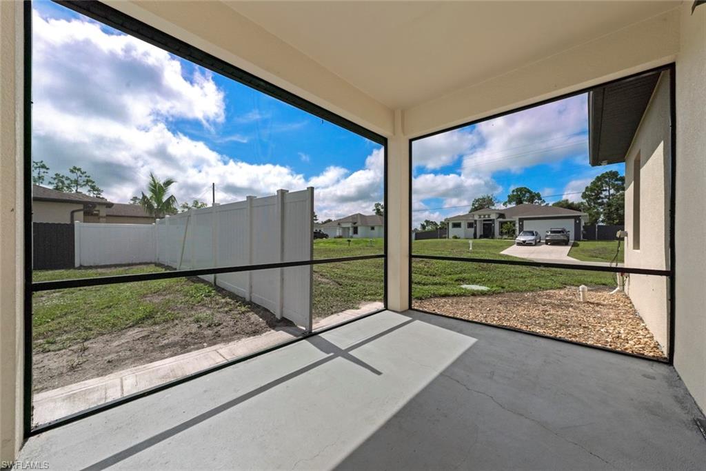 Screened lanai with a concrete flooring, white privacy fencing, and a view of the side yard