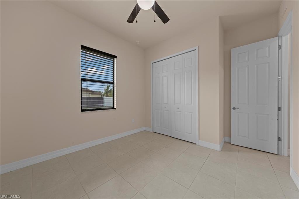 Cream-colored walls with white trim, ceiling fan, and tiled flooring