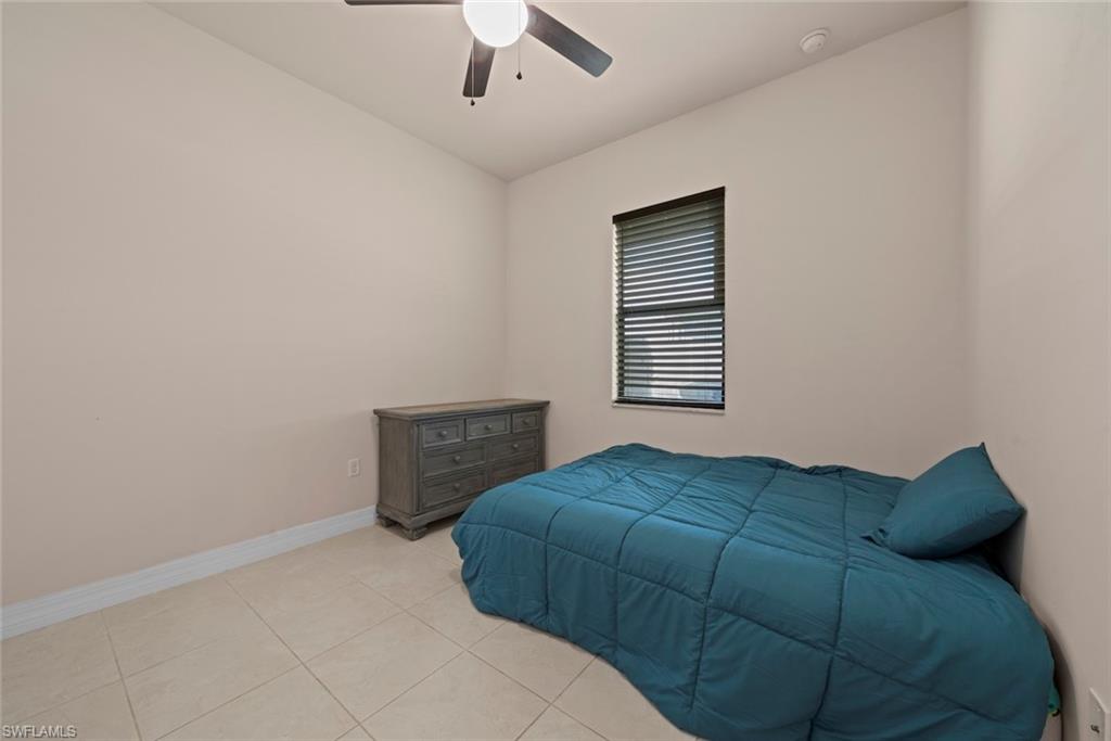 Ceiling fan, window with horizontal blinds, tile flooring, and neutral wall tones