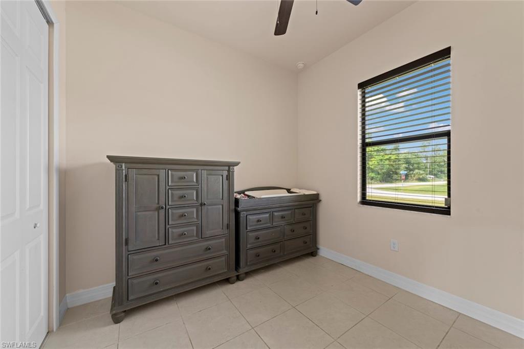Tile flooring, a single window with blinds, a ceiling fan, and a bi-fold closet door