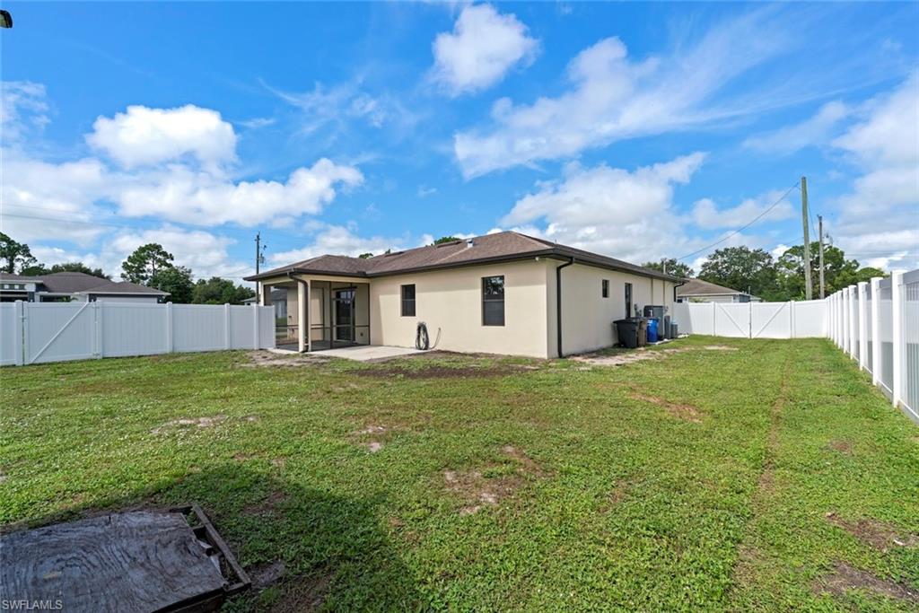 Expansive backyard featuring a full vinyl fence, concrete patio, and a screened lanai