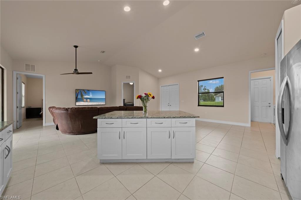 Open-concept living space with large format tile flooring, recessed lighting, and a ceiling fan