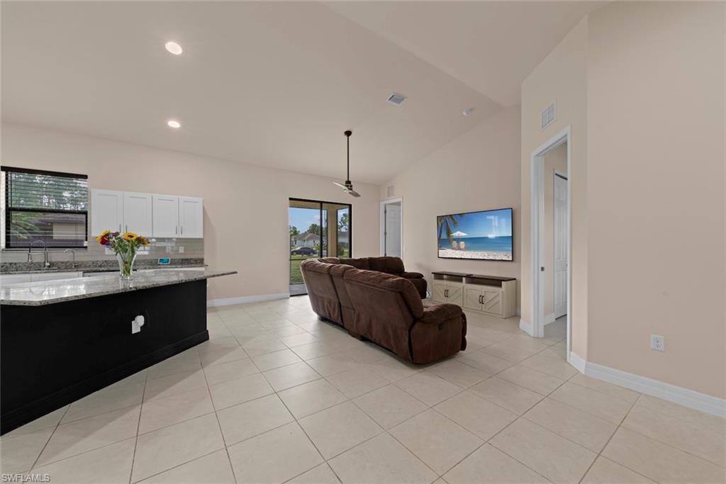 Open-concept living space with vaulted ceilings, neutral wall tones, and tiled flooring