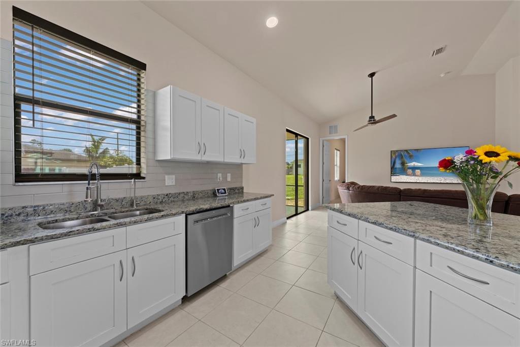 Kitchen featuring white cabinetry, granite countertops, stainless steel sink, tile flooring, and a stainless steel dishwasher