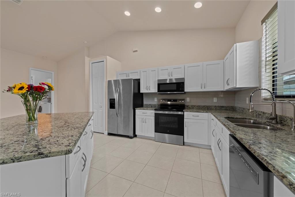 Kitchen featuring white cabinetry, stainless steel appliances, granite countertops, and tile flooring