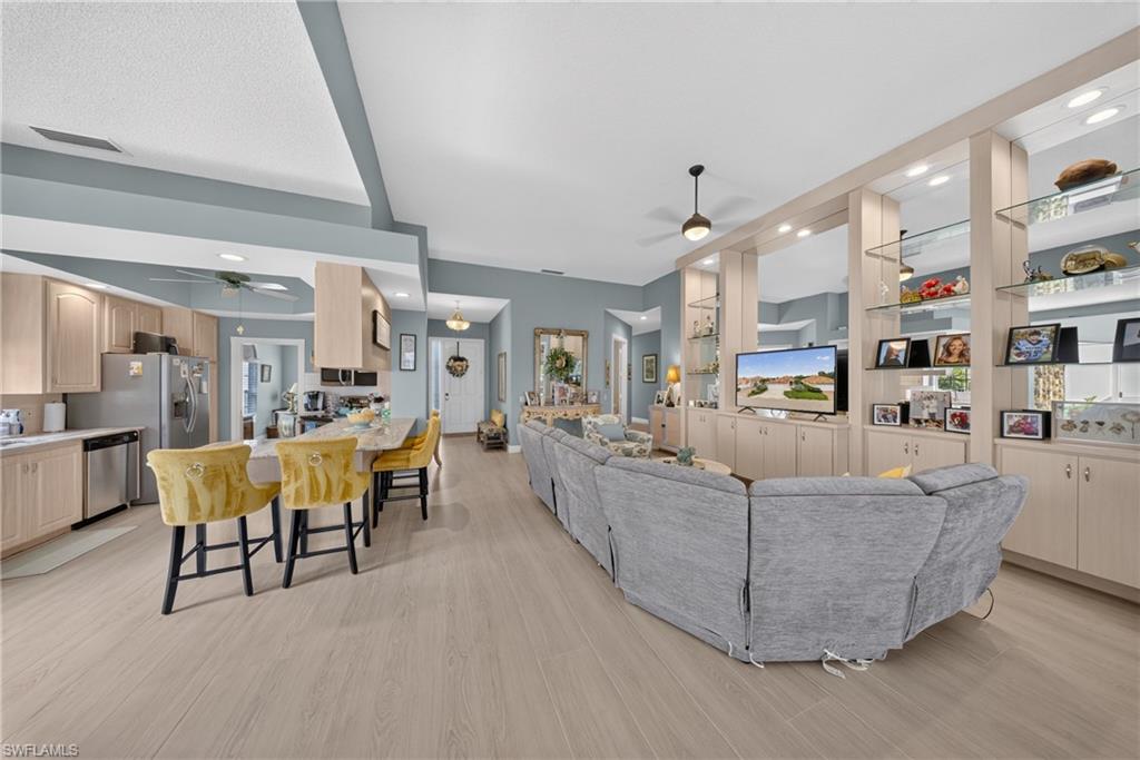 Open-concept living area featuring light wood-finish flooring, vaulted ceilings, and a neutral color palette