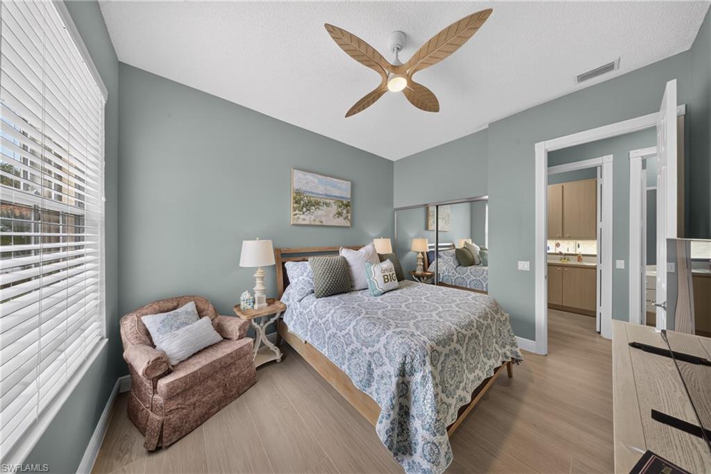 Bedroom with wood-finish flooring, a decorative ceiling fan, and a window with horizontal blinds