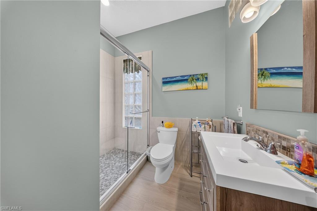 Bathroom featuring a glass-enclosed shower with pebble-finish flooring and a glass block window