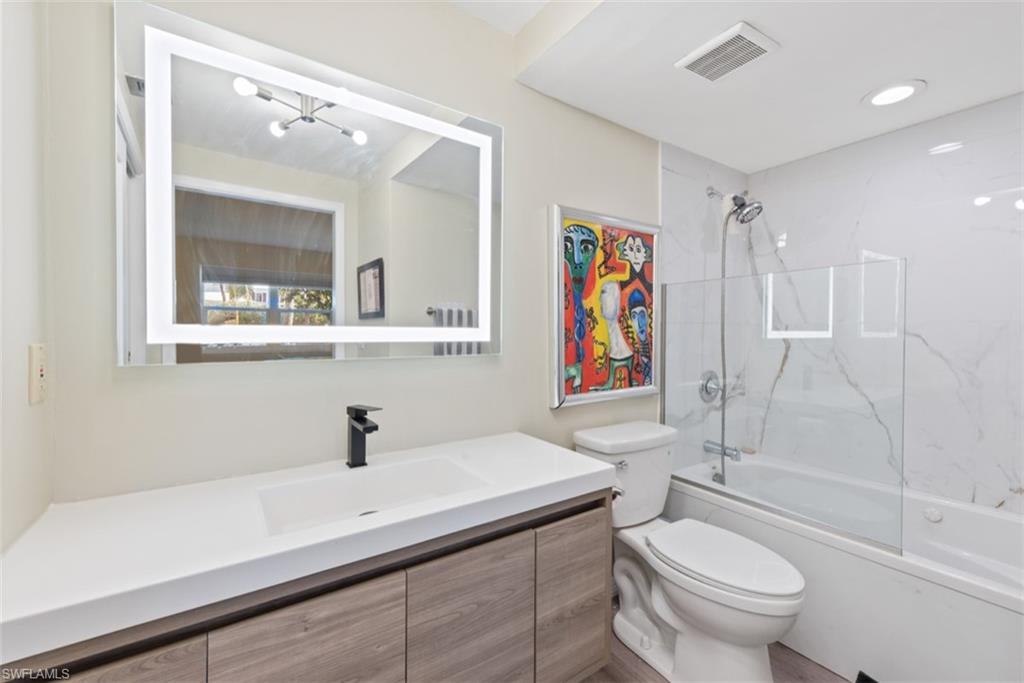 Full bathroom featuring vanity, toilet, and bath / shower combo with glass door