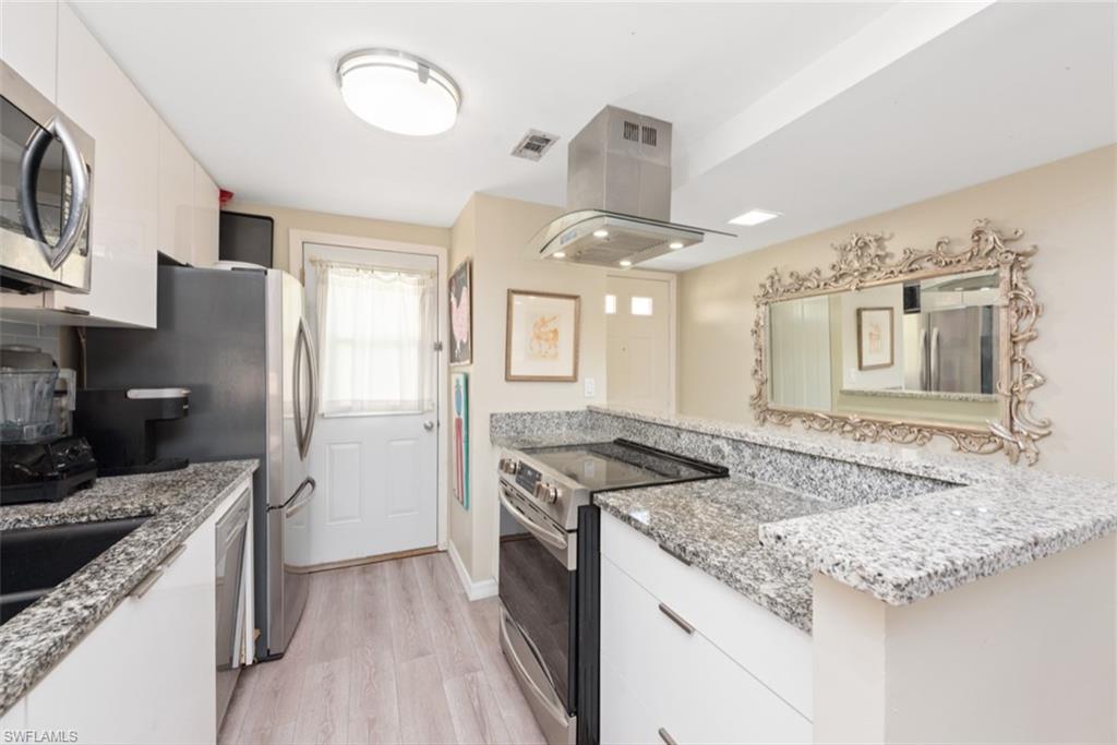 Kitchen featuring white cabinetry, stainless steel appliances, and island exhaust hood