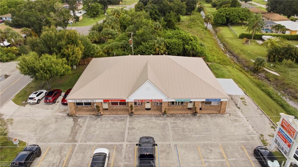Commercial building with a metal roof, brick facade, covered walkways, and a spacious paved parking lot
