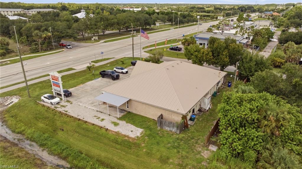 Single-story commercial building with a metal roof, brick exterior, and a gravel parking area
