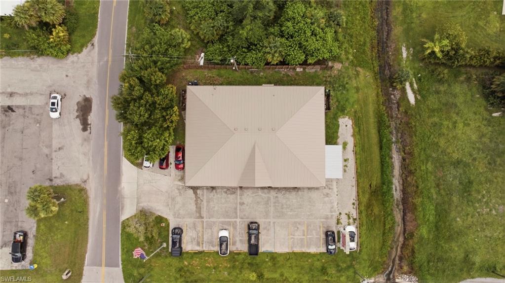 Building with a peaked roof, expansive paved parking, and surrounding green landscaping