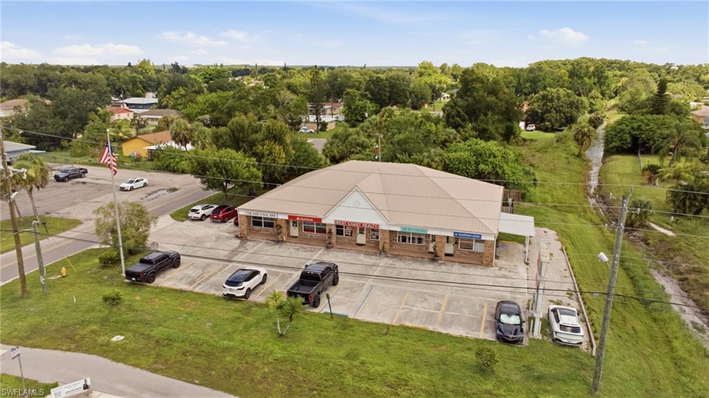 Multi-tenant commercial building with a beige-colored roof, brick facade, and an asphalt parking lot