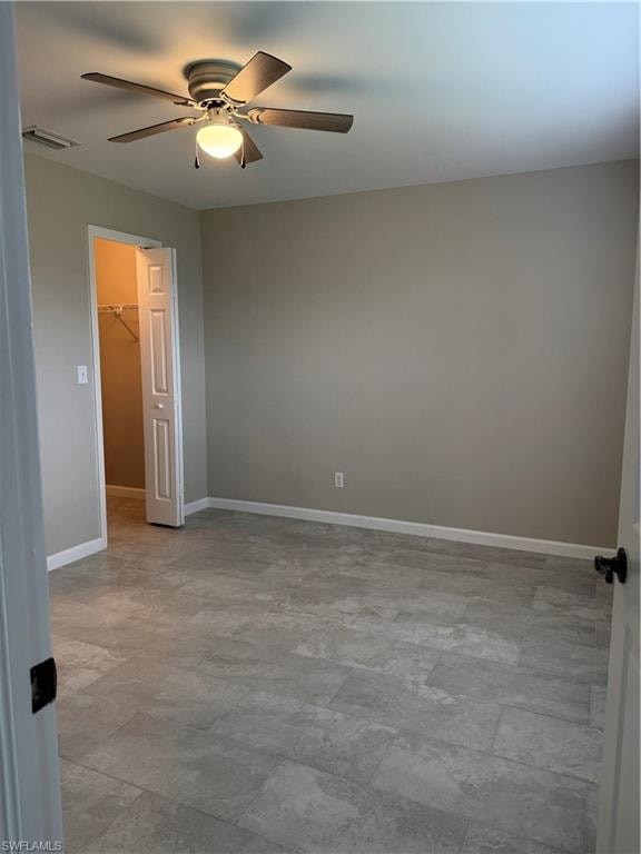 Second bedroom featuring a walk in closet and ceiling fan